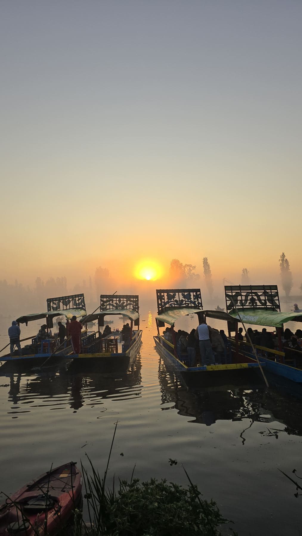 El sol sale sobre el lago frente a trajineras amarradas