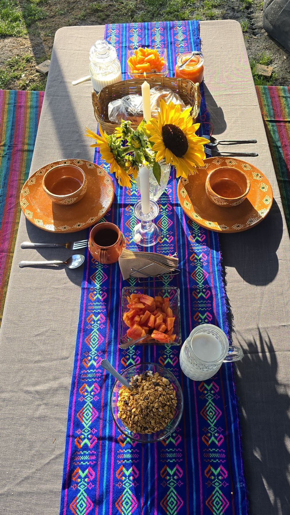 Mesa de desayuno con textil tradicional, girasoles y jarros de barro