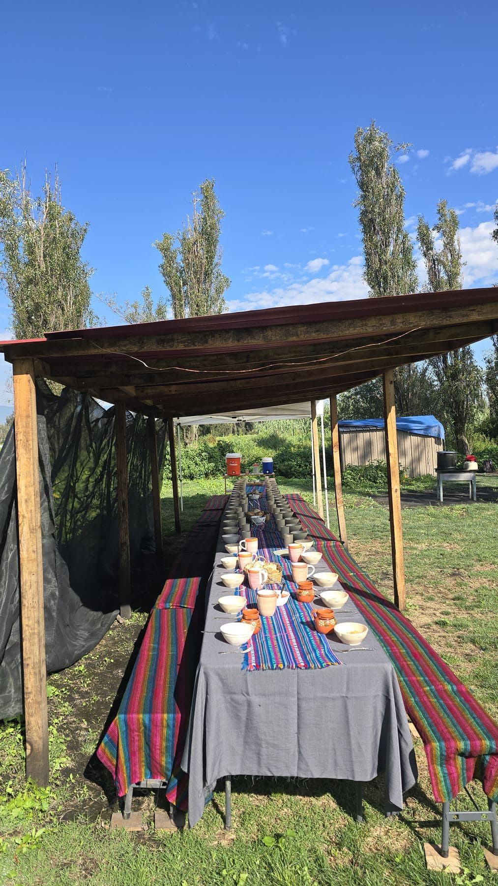 Mesa larga servida bajo un techo de lona en la chinampa